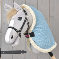 Grå käpphäst i svart grimma som bär det ljusblå quiltade stalltäcket Sky Blue med krämvit fleecekant