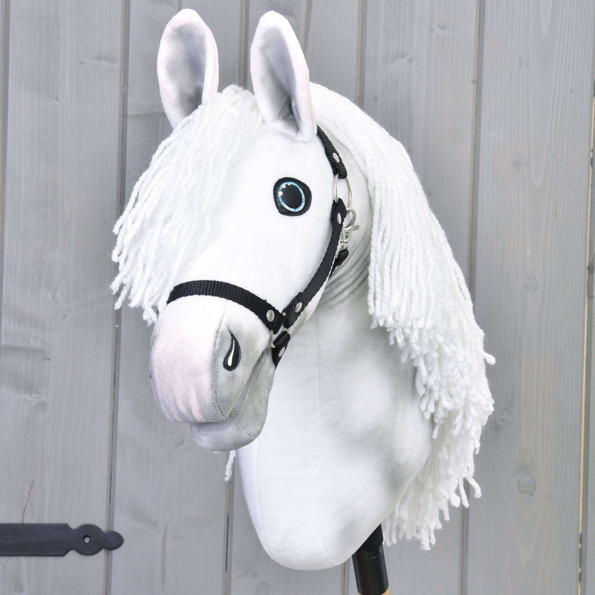 Hobby Horse Elektra med svart grimma framifrån, lång vit man av garn som faller på båda sidor om huvudet