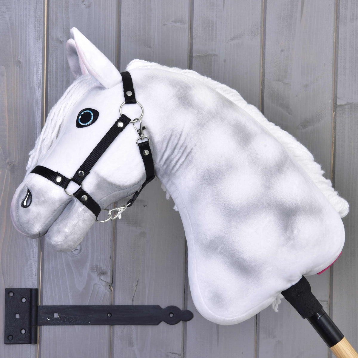 Hobby Horse Elektra med svart grimma sedd från sidan, med mjuka grå aplar på den vita plyschhalsen