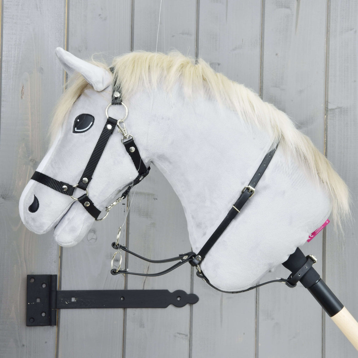 Martingale black on a light grey Hobby Horse in side view, the neck strap with buckle and two silver rings hanging in front