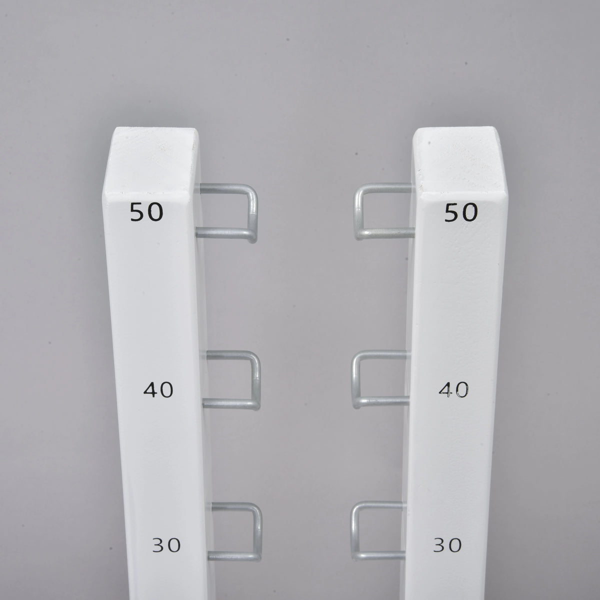 Närbild av de två hinderstödens toppar med svarta markeringar 30, 40 och 50 och U-formade metallkrokar mot varandra