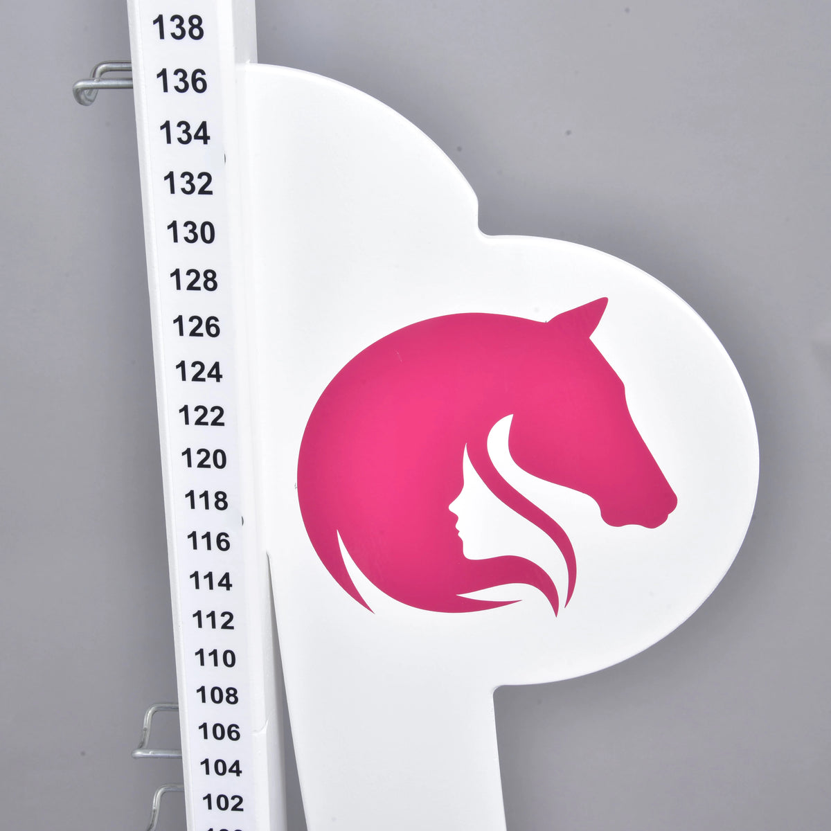 Närbild av en vinge med logotypen med rosa hästhuvud och flickprofil bredvid skalan från 102 till 138 cm