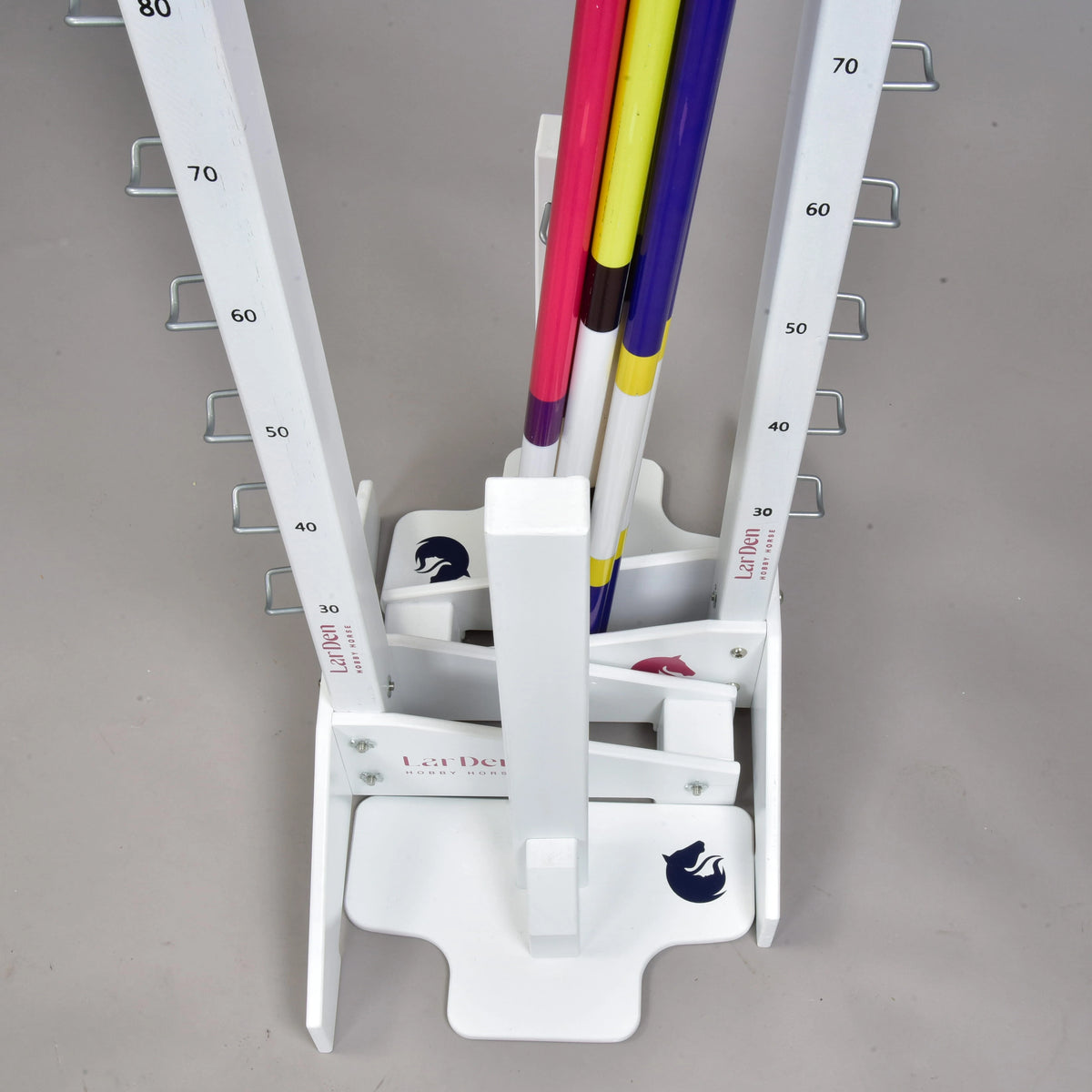 Close-up of the stored set from above: stacked white feet with blue and pink horse logos and the striped poles upright