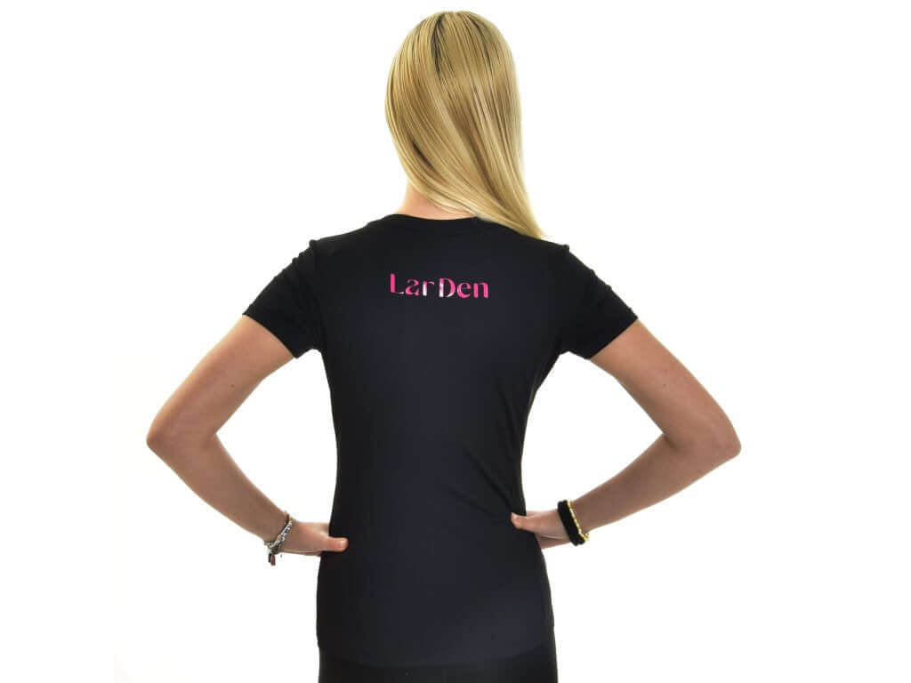 Blonde girl seen from behind, hands on hips, in the black Hobby Horse T-Shirt Active with pink back lettering