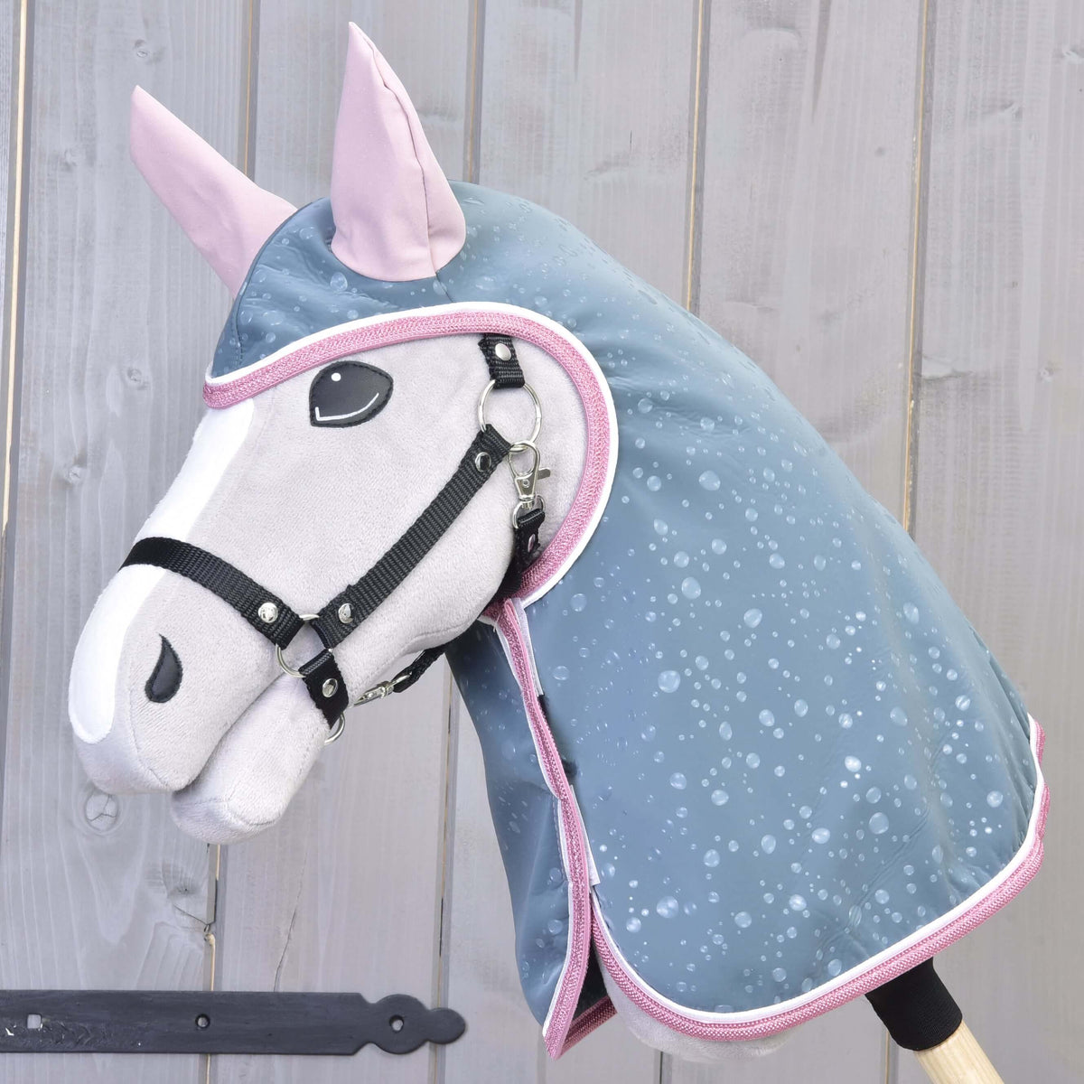Close view of the raincoat hood with pink ears and pink binding framing the face of a grey Hobby Horse