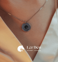 Horse head logo pendant worn on a slim chain inside the open collar of a light shirt