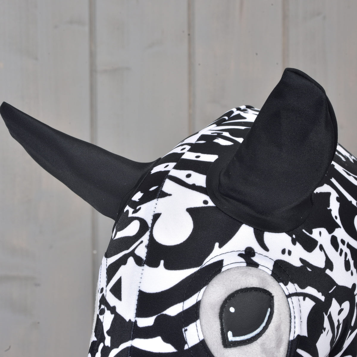 Close-up of the protective suit Black & White on a grey head: two black ears and the embroidered eye in the eye opening