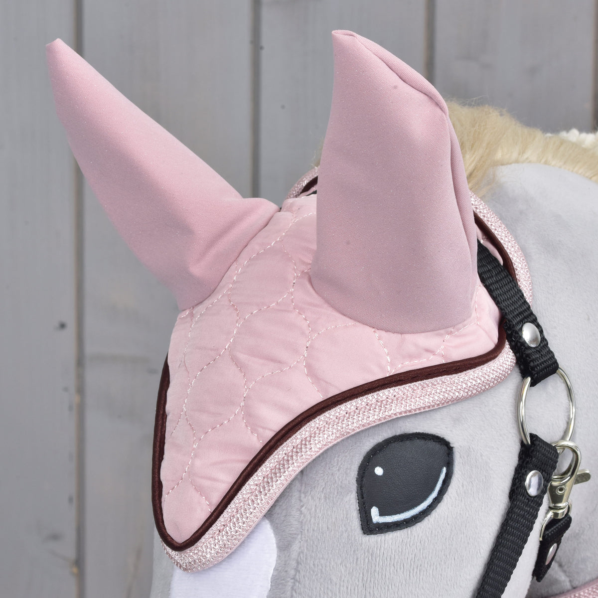 Close-up of the pink quilted ear bonnet from Set Blush with pink fabric ears and brown piping on a grey Hobby Horse