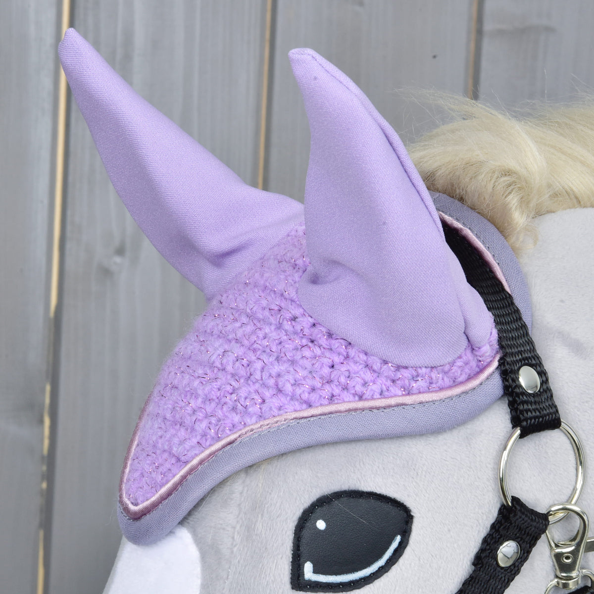 Close-up of the lilac crochet with glitter thread, the fabric ears and the pink piping beside the black halter