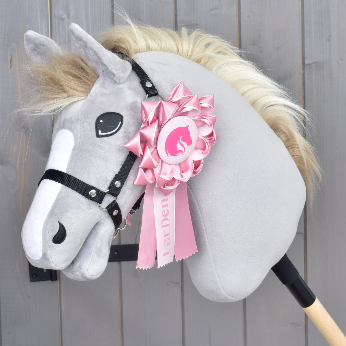 Hobby Horse Ribbon LarDen Pink pinned to the black halter of a grey plush head with a white blaze and blond mane