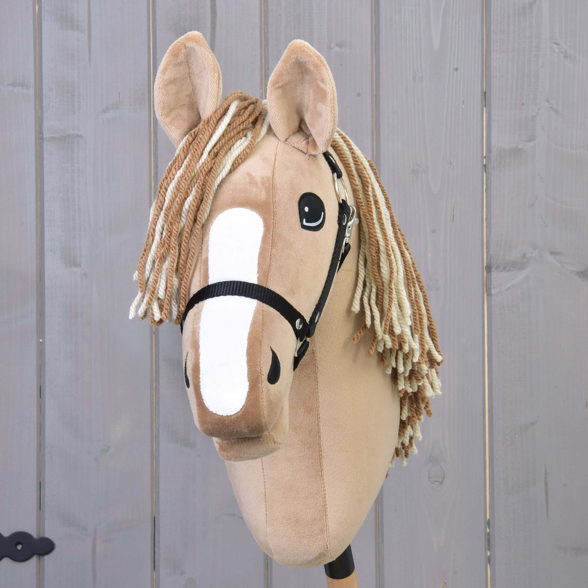 Hobby Horse Bren med svart grimma framifrån, bred vit bläs och tvåfärgad pannlugg av brunt och krämfärgat garn