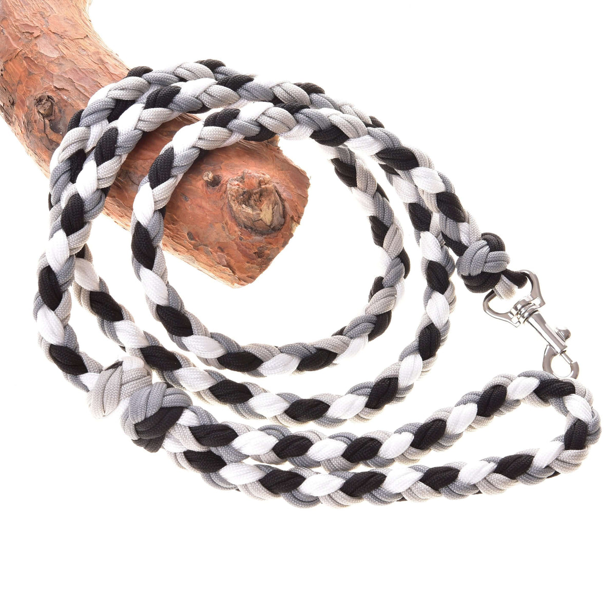 Flätat grimskaft svart/vitt för Hobby Horse från LarDen, ett grimskaft av paracord med grå detaljer och silverfärgad hake draperat över en gren