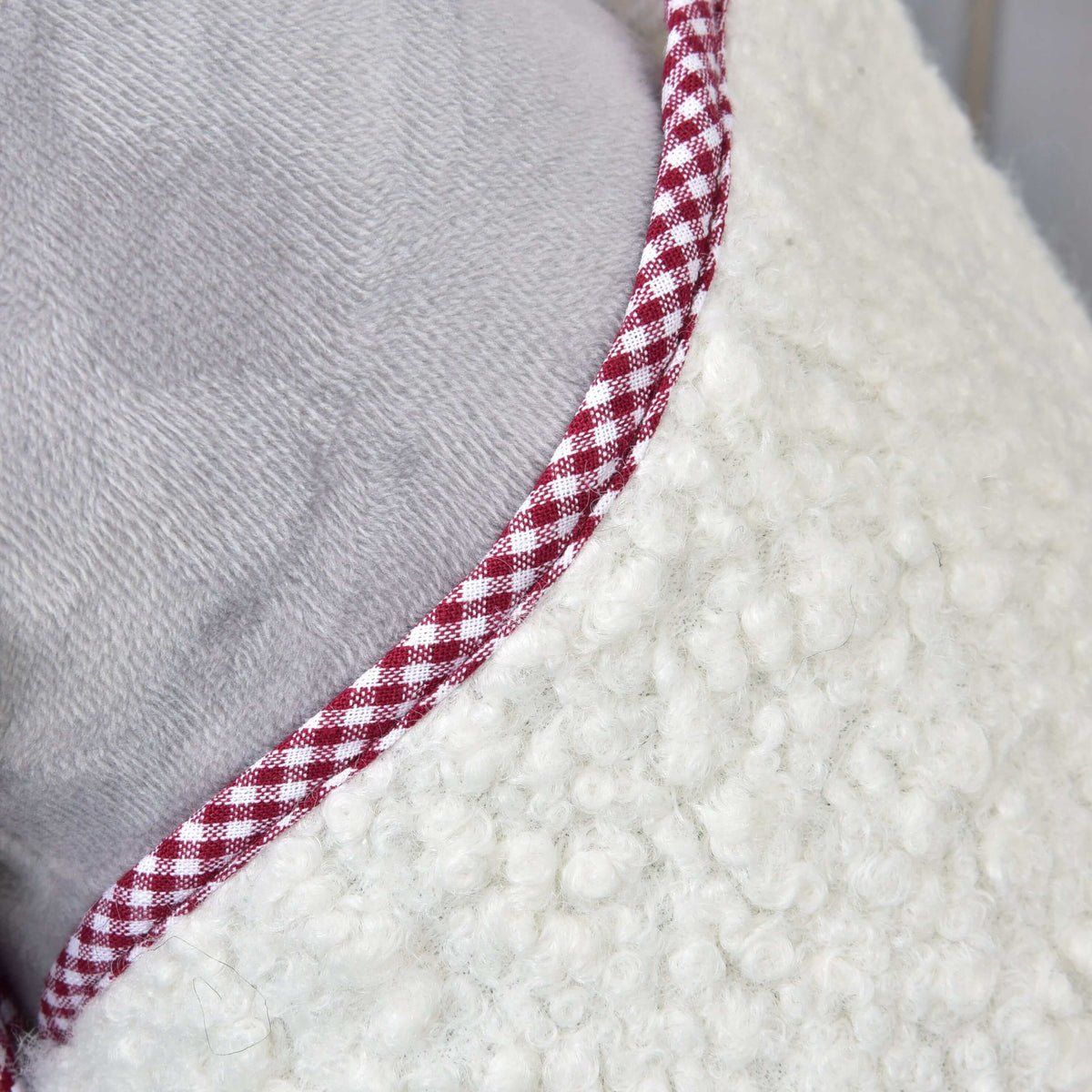 Close-up of the Hobby Horse Blanket cube red neckline with red and white gingham piping on cream curly fleece