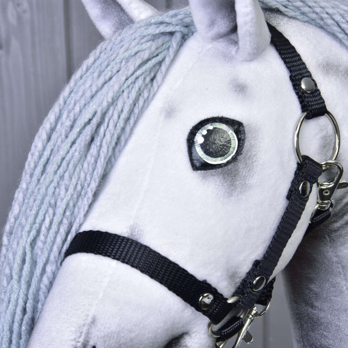 Närbild på ögat och den svarta grimman på Hobby Horse enhörning Silver, ljusgrå man av garn med fint silverglitter