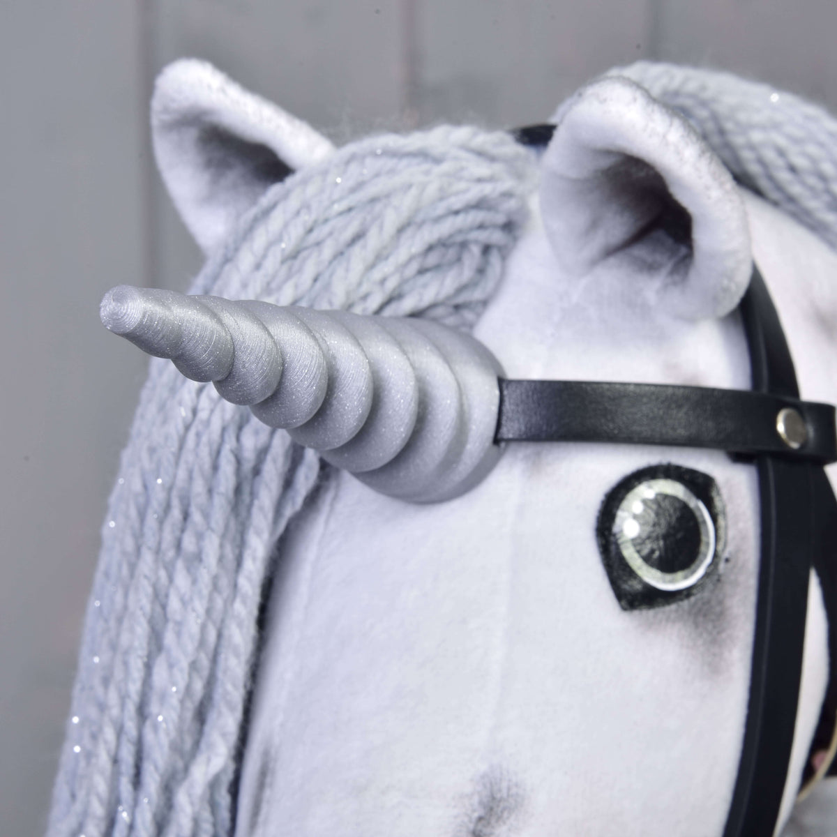 Närbild på det silverfärgade spiralhornet på Hobby Horse enhörning Silver, fäst på det svarta tränset mellan öronen