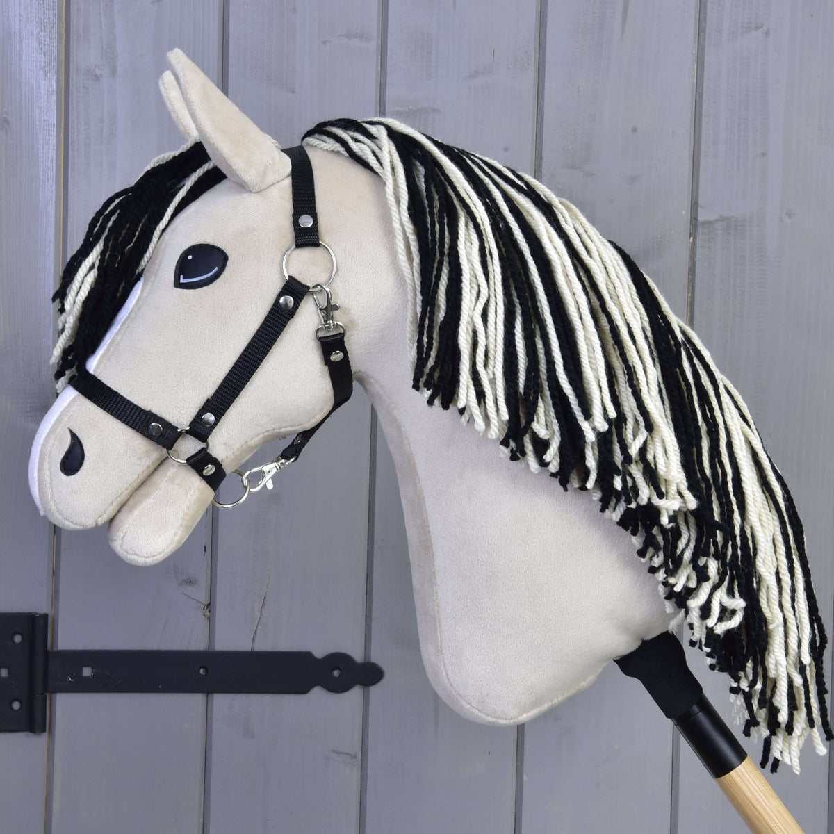 Side profile of Hobby Horse Aurora with a cream head, black halter and long black and white yarn mane down the neck