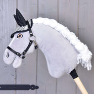 A grey plush Hobby Horse with a white braided mane and black halter wears the black and white houndstooth ear bonnet