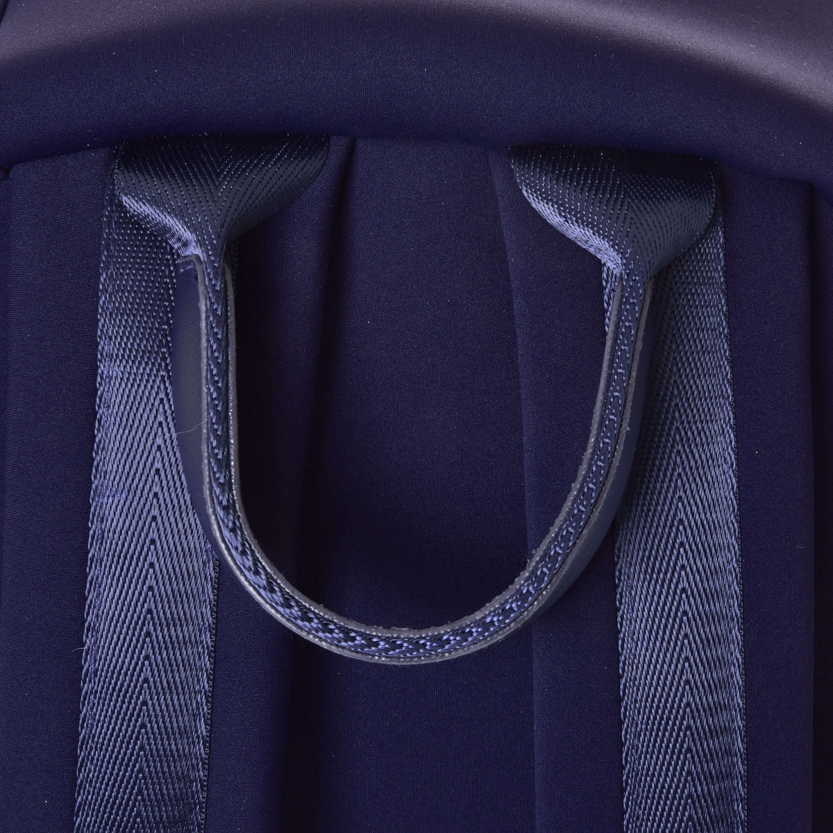 Close-up of the navy webbing carry handle between the shoulder straps of the Hobby Horse Backpack
