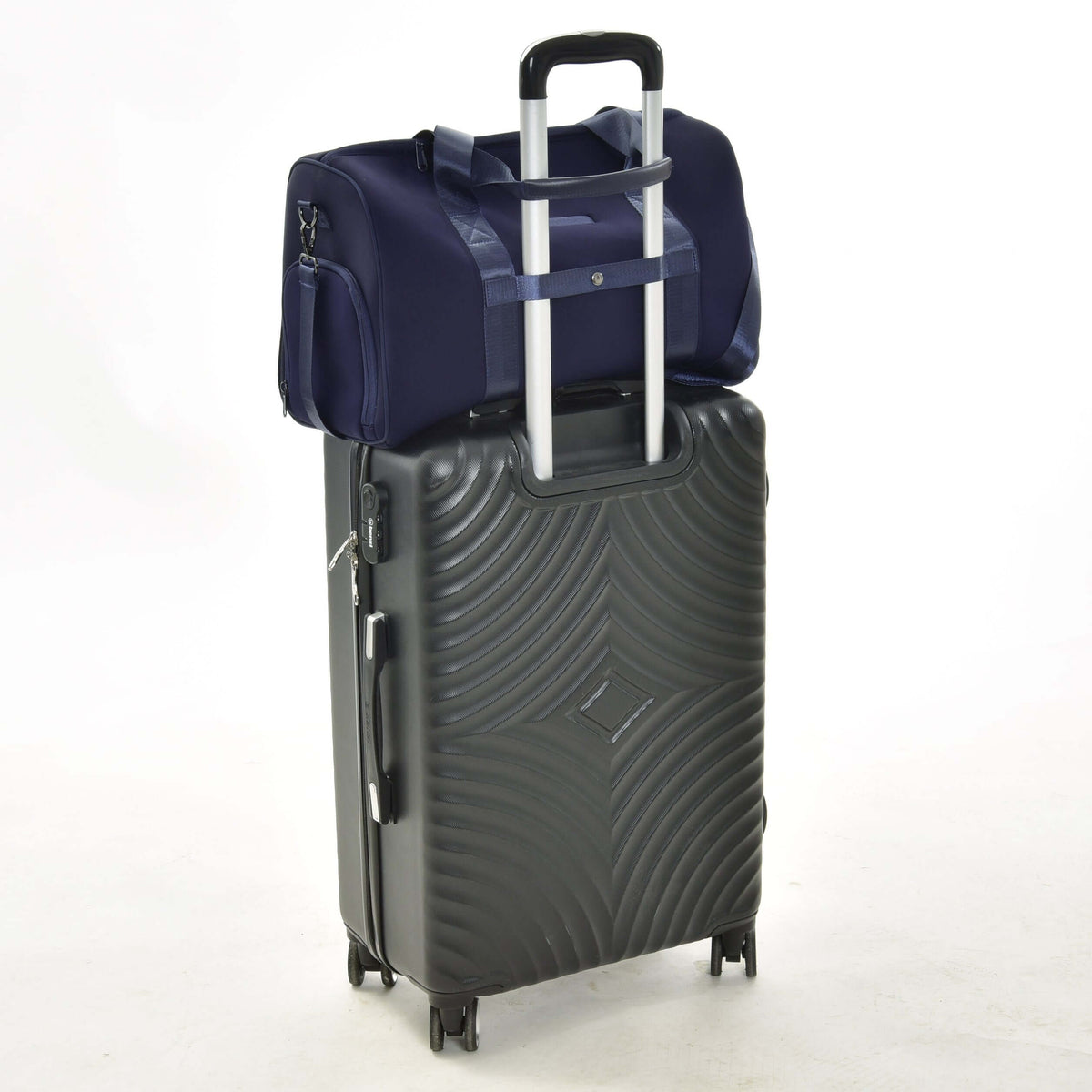 Navy Hobby Horse Sports bag riding on a black rolling suitcase, its back strap slipped over the telescopic handle