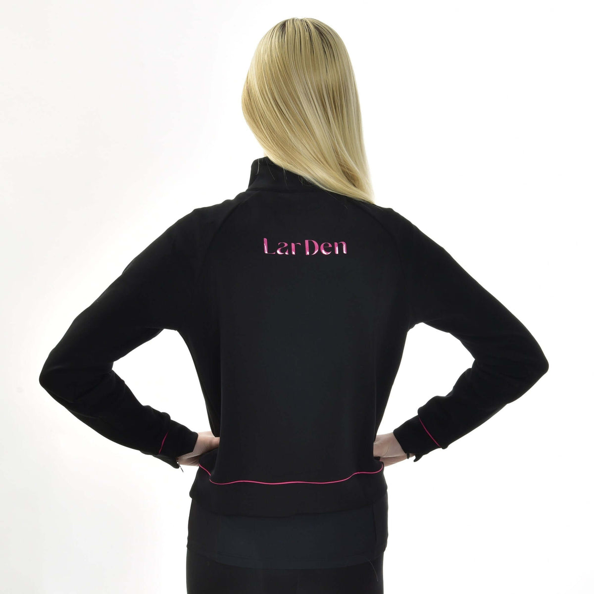 Blond flicka sedd bakifrån med händerna i sidan, i den svarta Hobby Horse sweatshirten LarDen med rosa text på ryggen