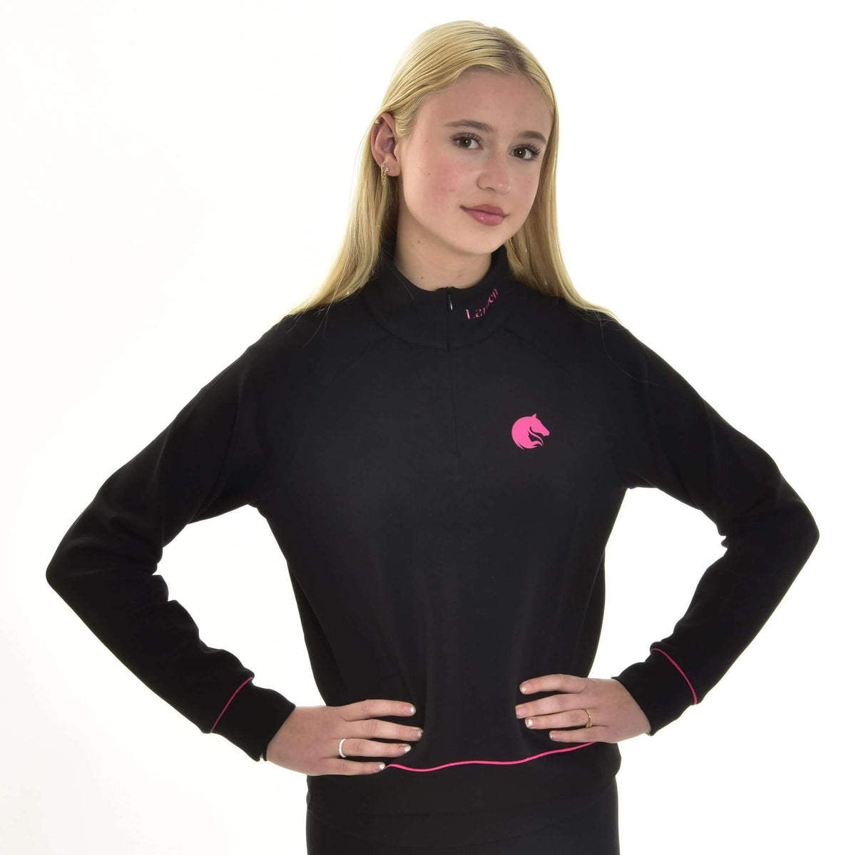 Blond flicka med händerna i sidan i den svarta Hobby Horse sweatshirten, rosa hästhuvudslogga på bröstet och rosa passpoal