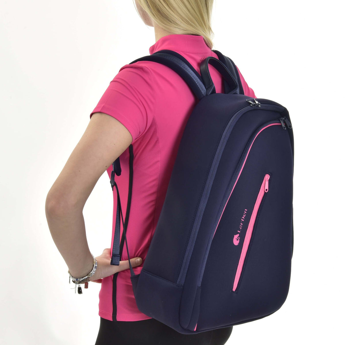 Blonde girl in a pink sports shirt wearing the navy Hobby Horse Backpack on her back, seen from the side