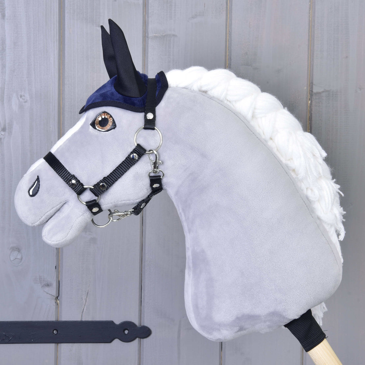 Grey Hobby Horse in a black halter wearing only the dark blue ear bonnet with black ears