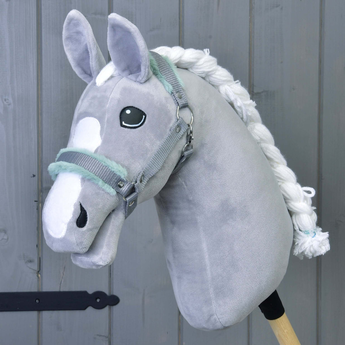 A grey plush Hobby Horse with a white blaze and braided mane wears the grey halter with mint green fur