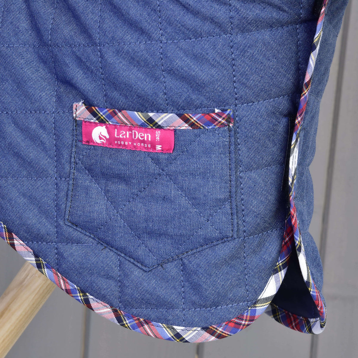 Detalj av fickan på täcket ur Hobby Horse Set Jeans med rosa etikett från LarDen, rombformad quiltning och röd-blå skotskrutig kant