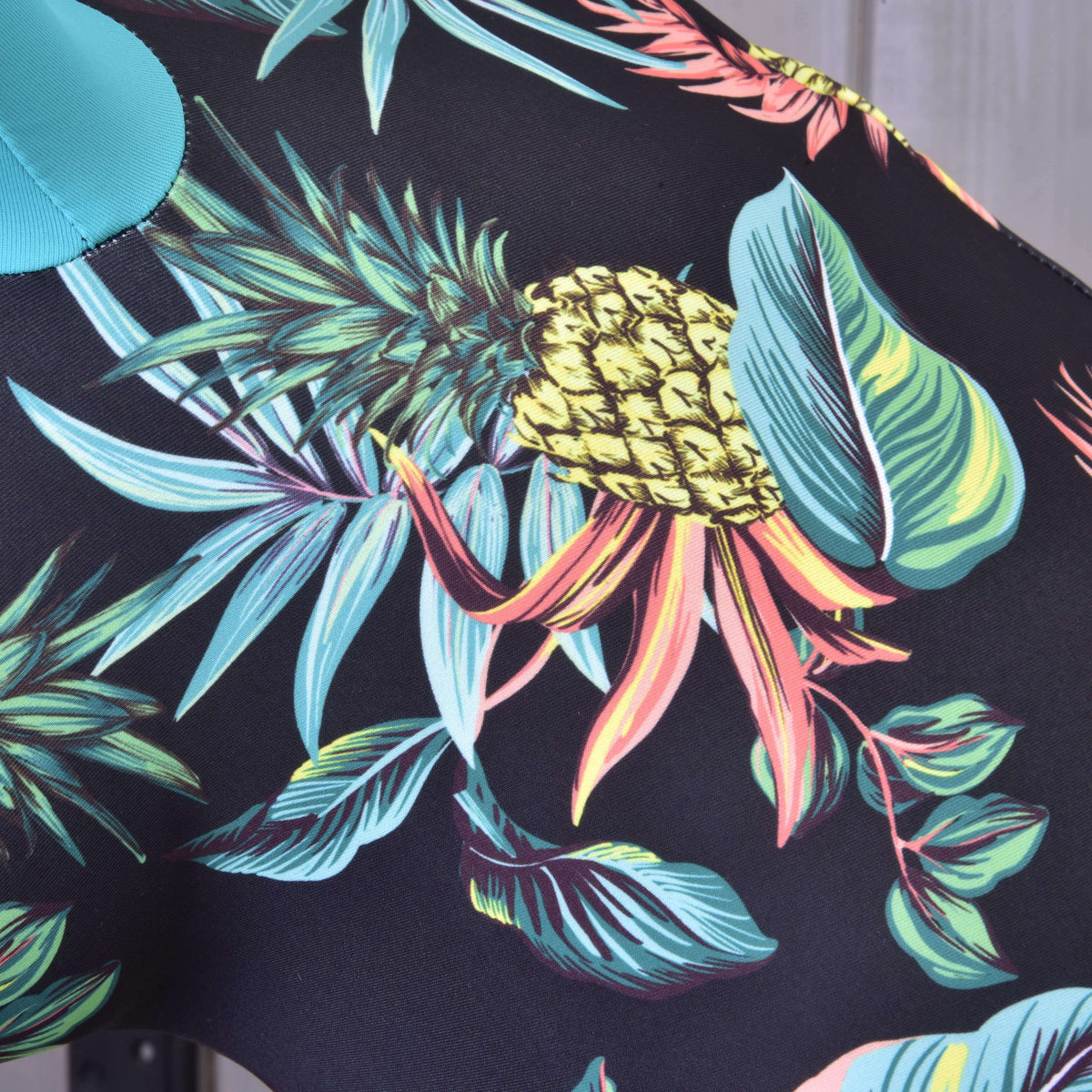 Print detail of the Hobby Horse protective suit Pineapple: yellow pineapple, turquoise and coral leaves on black Lycra