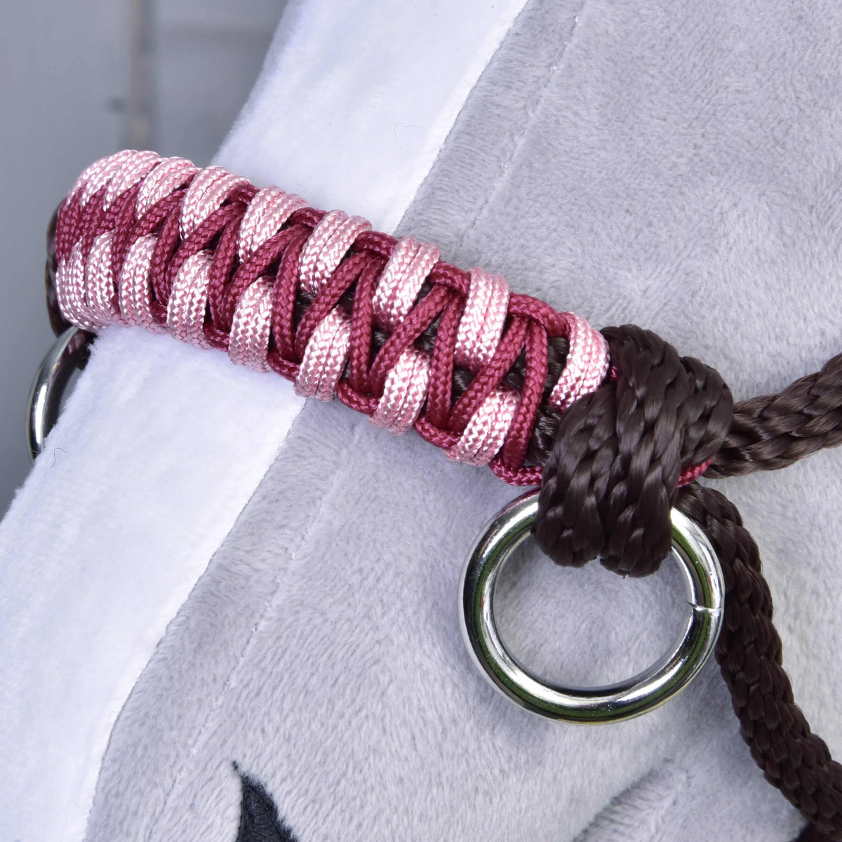 Close-up of the pink and burgundy braided noseband with a silver ring and dark brown knot on a Hobby Horse