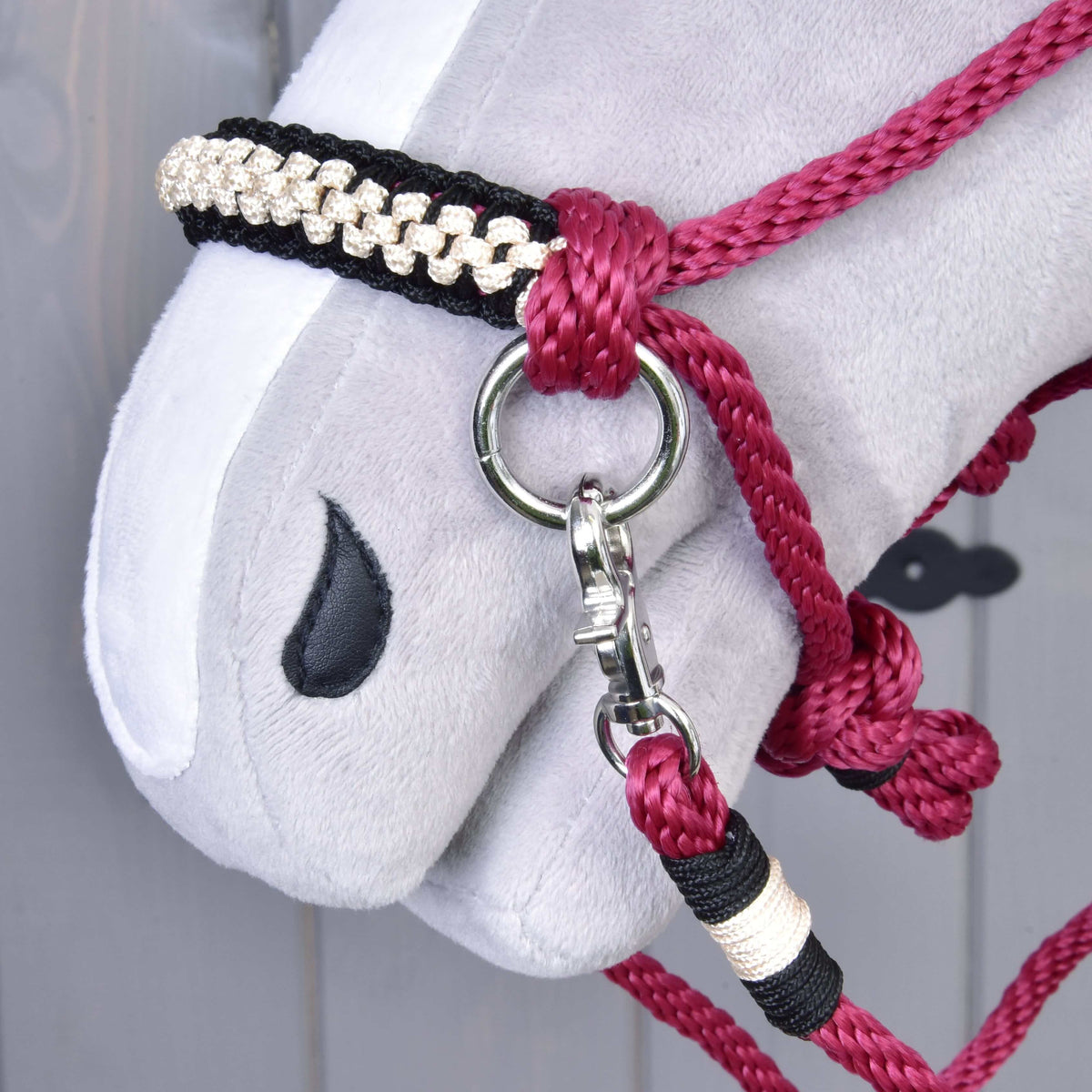 Close-up of the black and cream braided noseband and snap hook of Rope set Burgundy on a grey Hobby Horse
