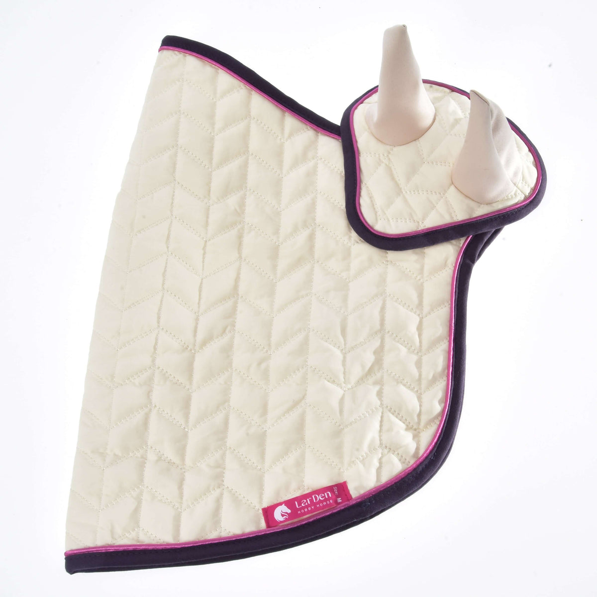 Set Supreme Crema laid flat, a cream quilted blanket with the ear bonnet on top and a pink LarDen label