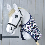 Grey Hobby Horse with a cream mane and black halter wearing the Indian blanket, seen from the front at a grey wooden door