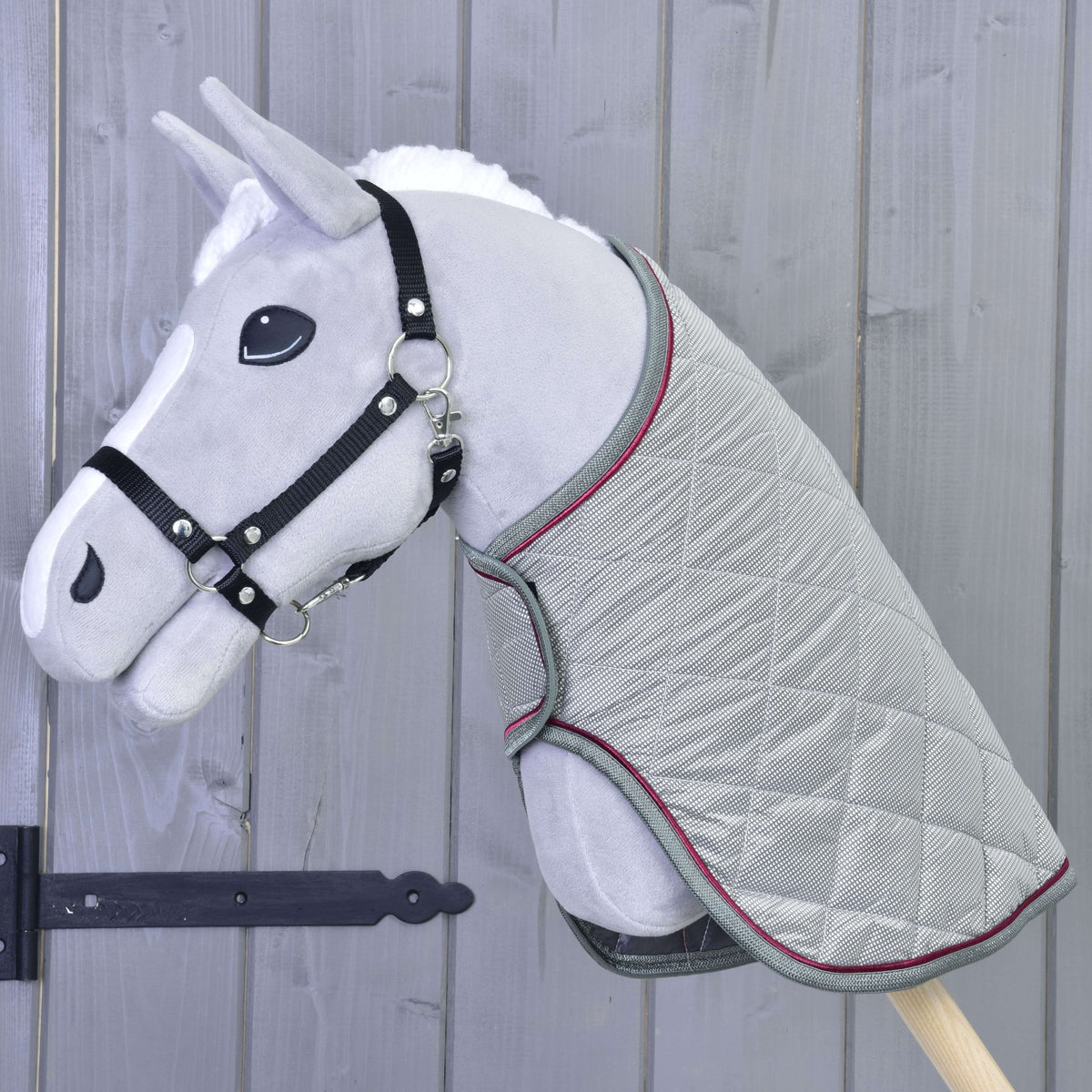 Light grey Hobby Horse in a black halter wearing the silver grey quilted blanket with grey and raspberry trim