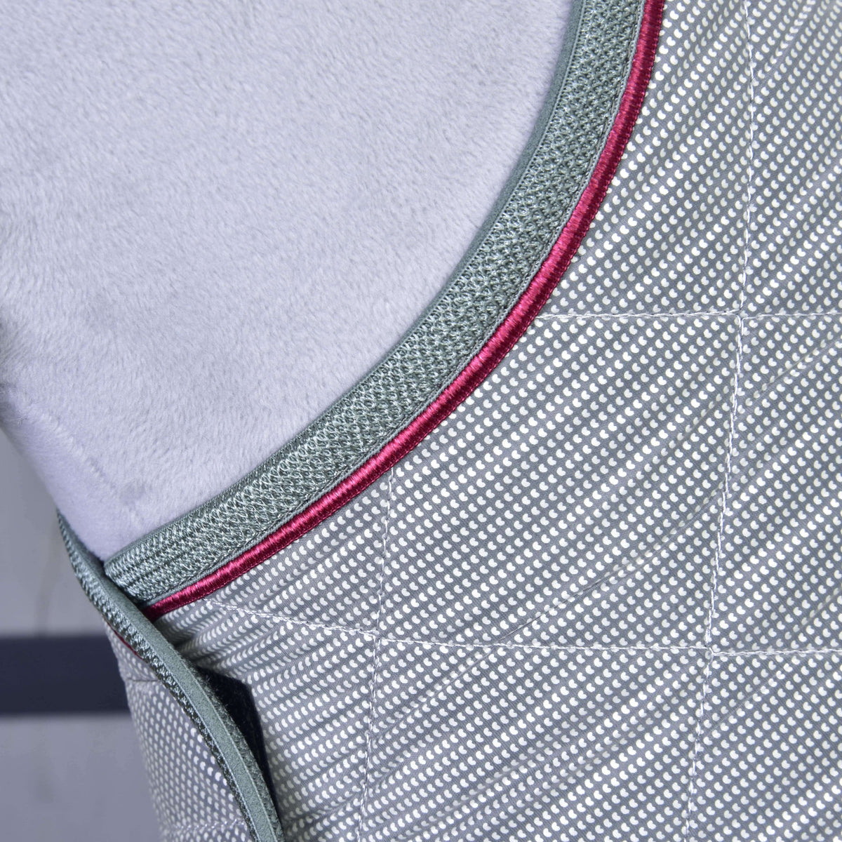 Close-up of the grey binding and raspberry piping along the front edge of the dotted silver blanket