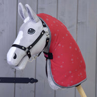 Grey Hobby Horse in a black halter wearing the raspberry red dotted stable blanket with grey binding