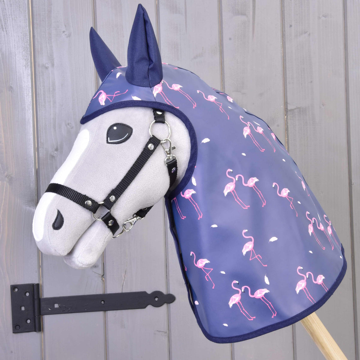 Grey Hobby Horse in a black halter wearing the blue-violet raincoat with pink flamingo print and navy ear covers
