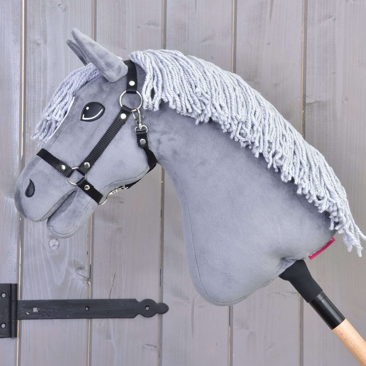 Hobby Horse Grace i vänsterprofil med lång ljusgrå man av garn över den grå halsen och svart grimma