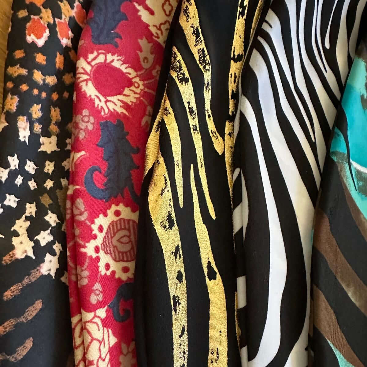 Close-up of five patterned fabrics: animal print, red paisley, gold tiger stripes, zebra and turquoise-brown stripes