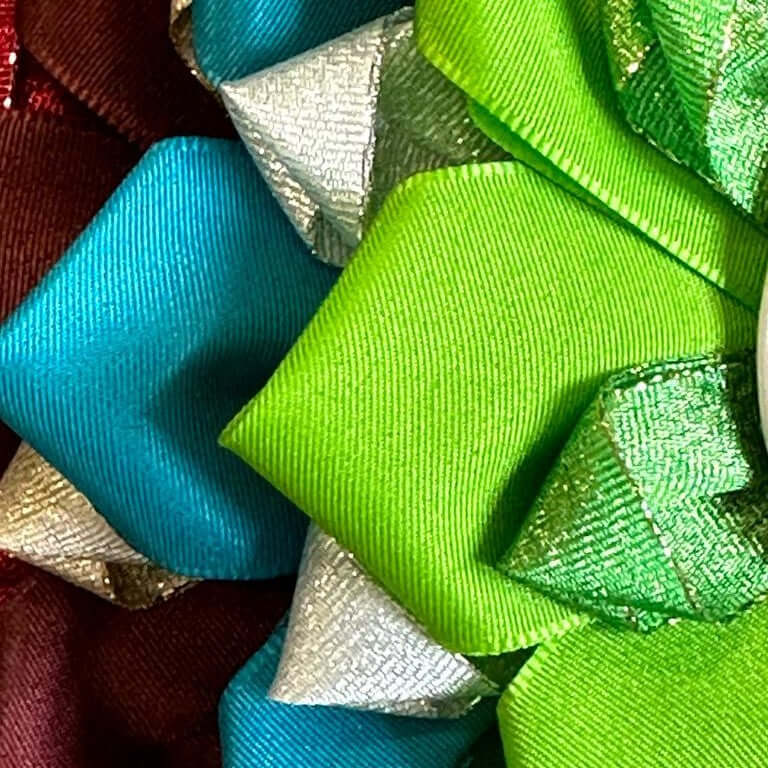 Close-up of pleated rosette ribbons in turquoise, lime green, silver, metallic green and burgundy satin