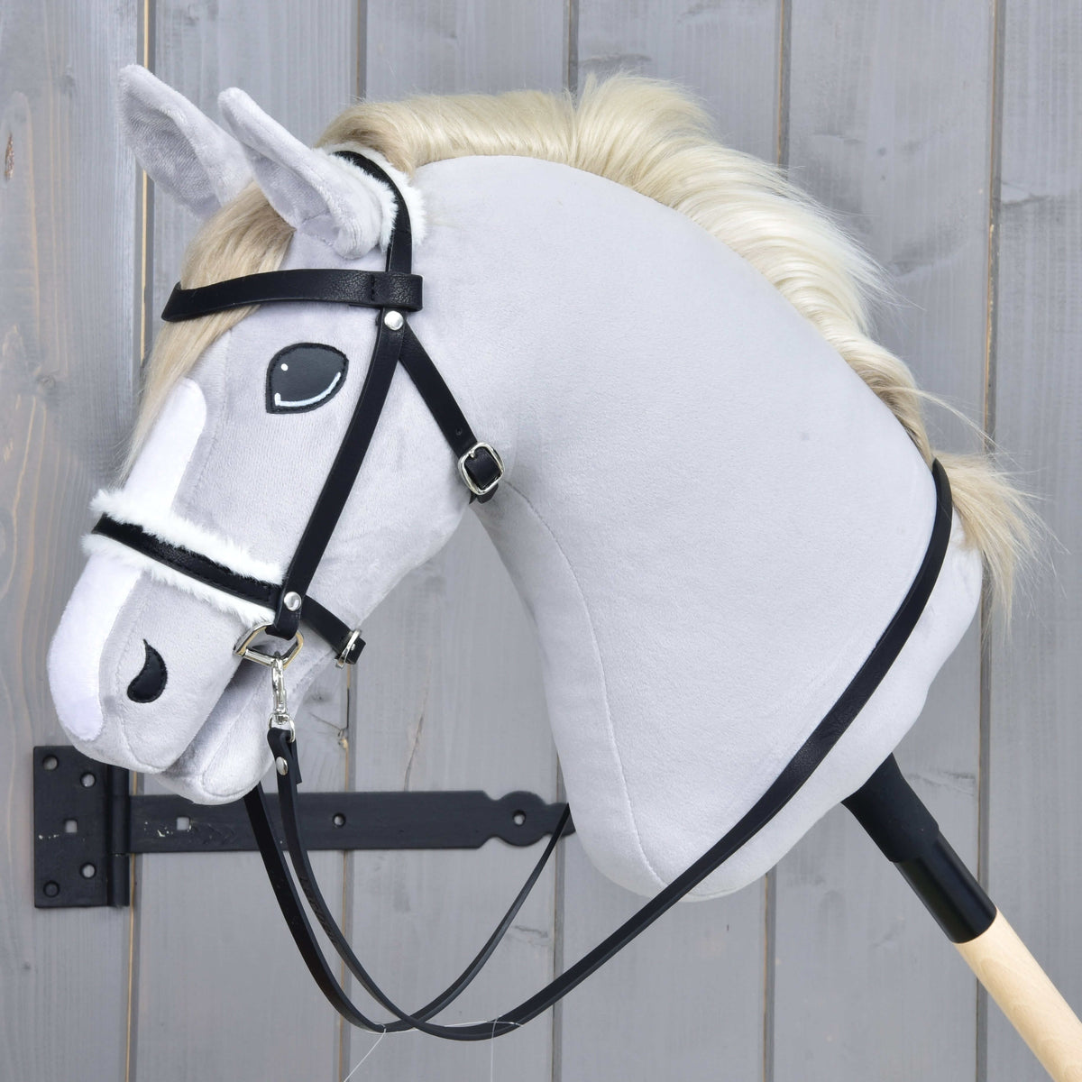 Hobby Horse komplett träns med päls från LarDen, svart med nosgrimma i vit päls och tyglar, på ett grått käpphästhuvud i plysch