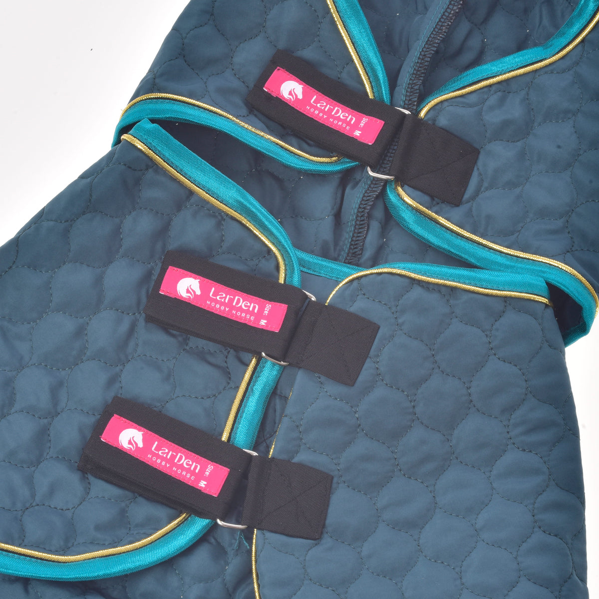 Three black straps with pink LarDen labels on the Hobby Horse Lagoon blanket, laid flat with turquoise binding and gold piping
