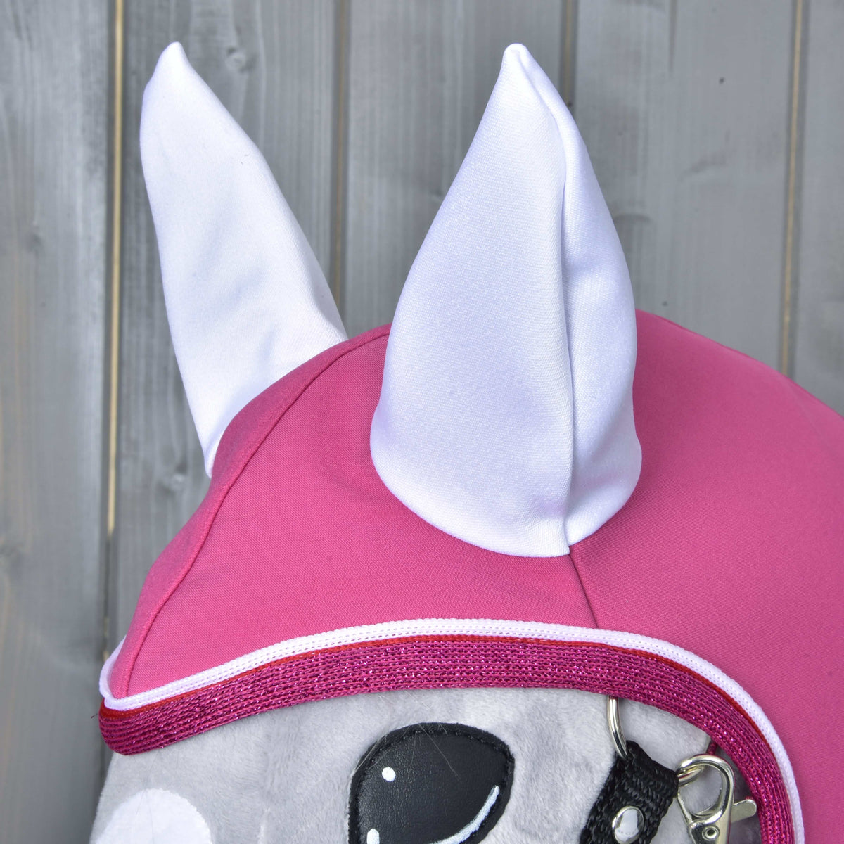 Close-up of the Raincoat LarDen hood on a grey Hobby Horse: white ears on raspberry pink with glittery pink binding