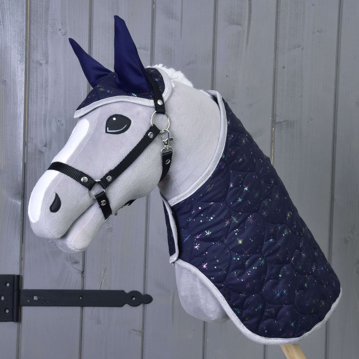 Grey plush Hobby Horse with a black halter wearing the navy Set Magic blanket and ear bonnet with sparkling stars