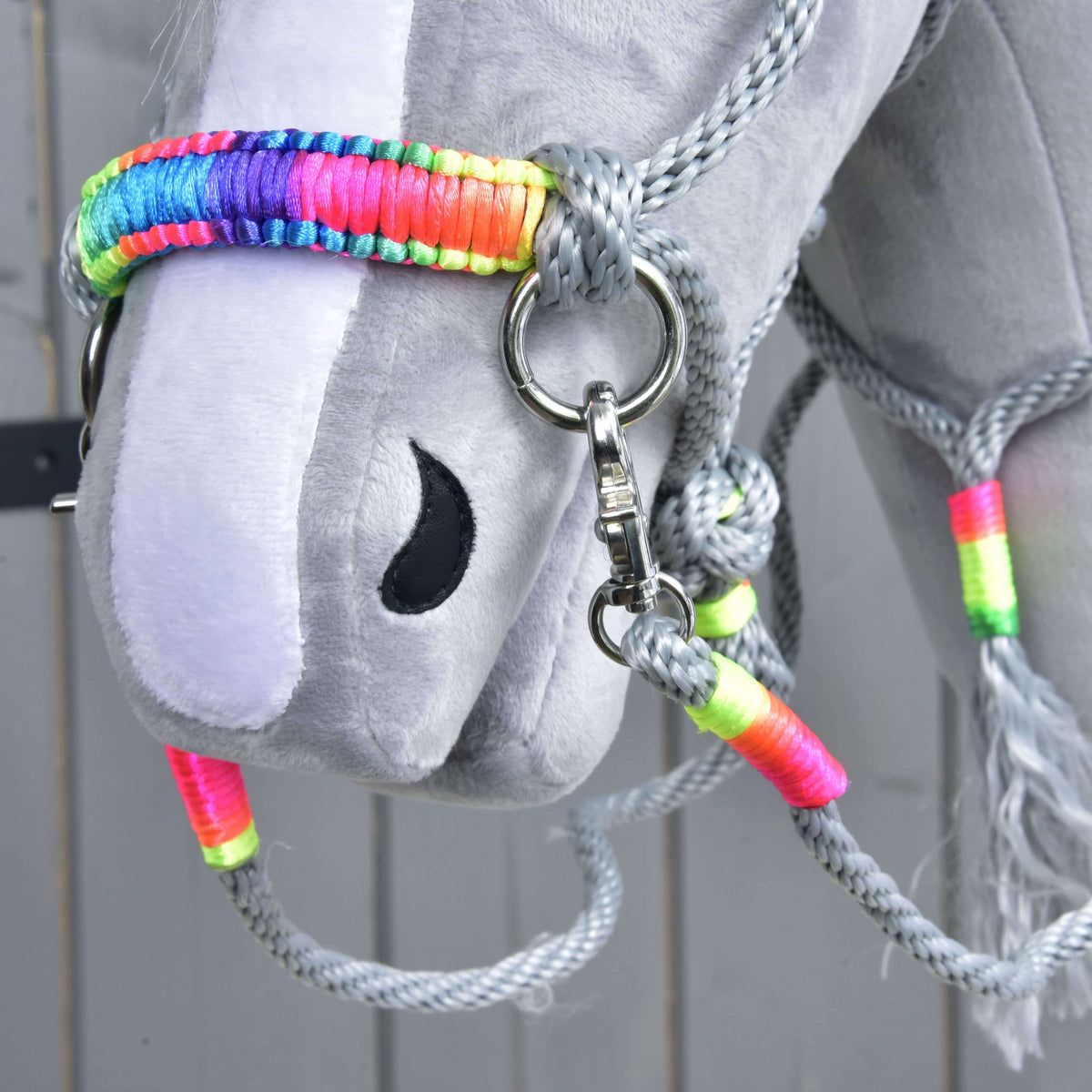 Close-up of the rainbow wrapped noseband of Rope set Manhattan on a grey Hobby Horse, with grey rope reins and neon wraps
