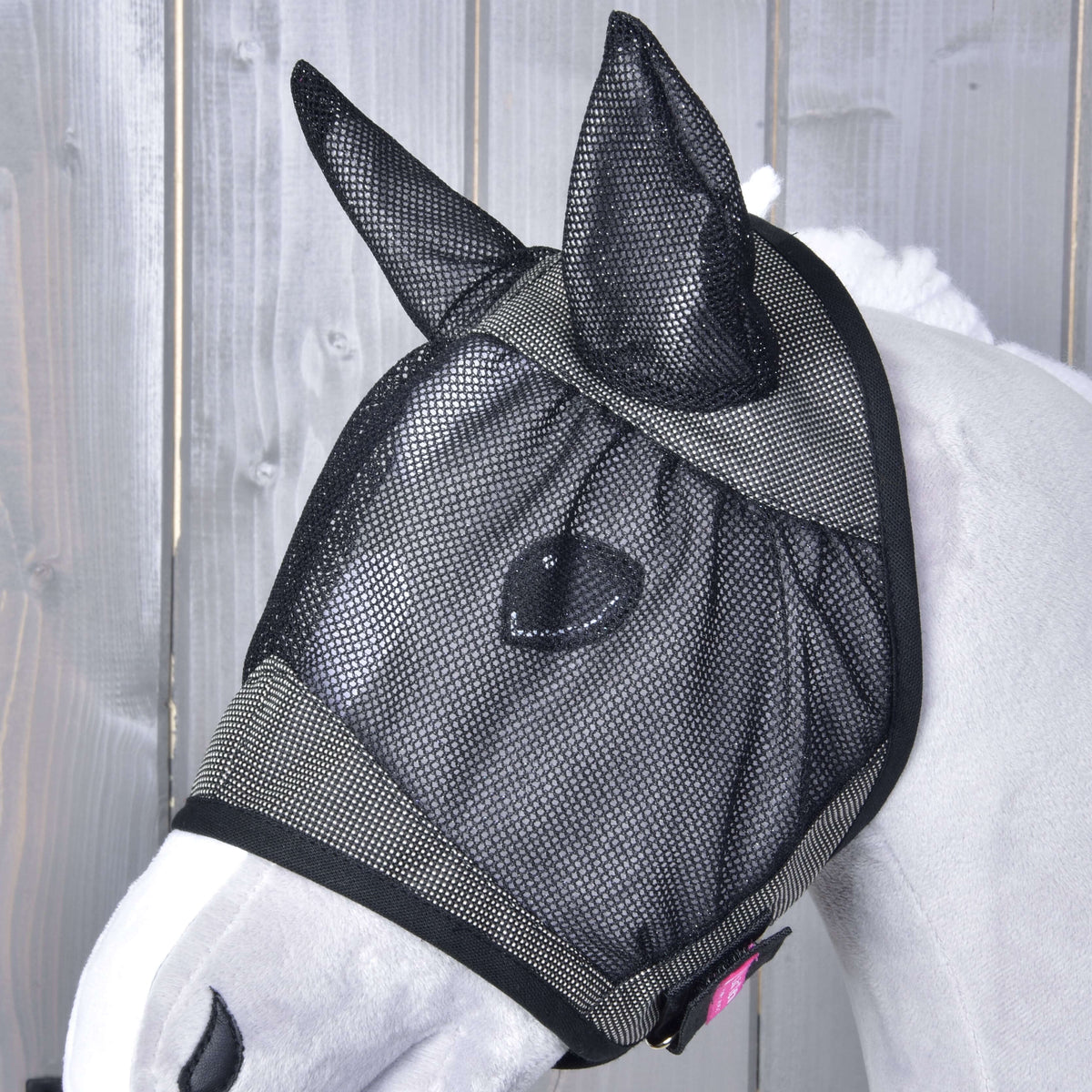 Hobby Horse flugmask De Luxe Grey på nära håll på en ljusgrå käpphäst: svarta nätöron, ögonnät och en liten rosa lapp