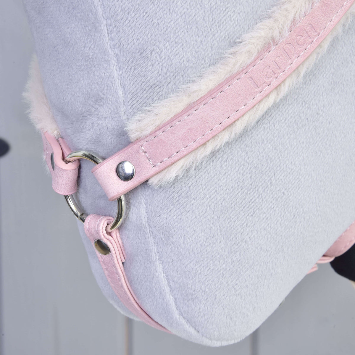 Close-up of the pink leatherette breastgirth strap with cream fur lining, embossed lettering and a silver ring