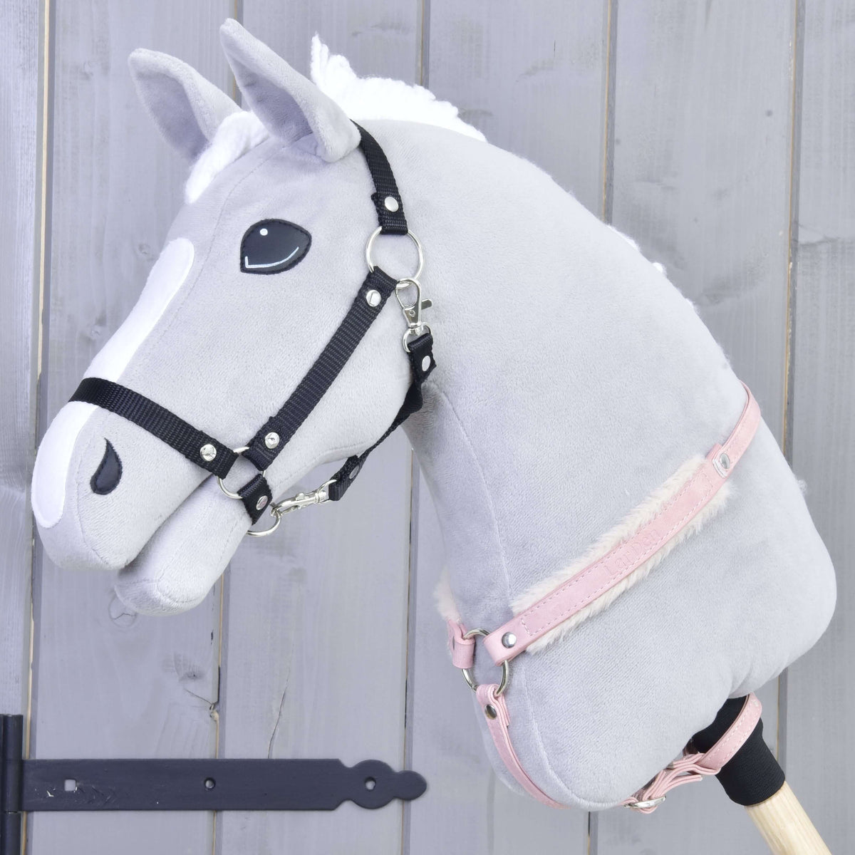 Grey Hobby Horse with a black halter wearing the pink leatherette breastgirth with fur around its neck