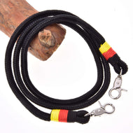 Hobby Horse Reins Emblem by LarDen: black rope reins with yellow and red wraps and two silver snap hooks, draped on a branch
